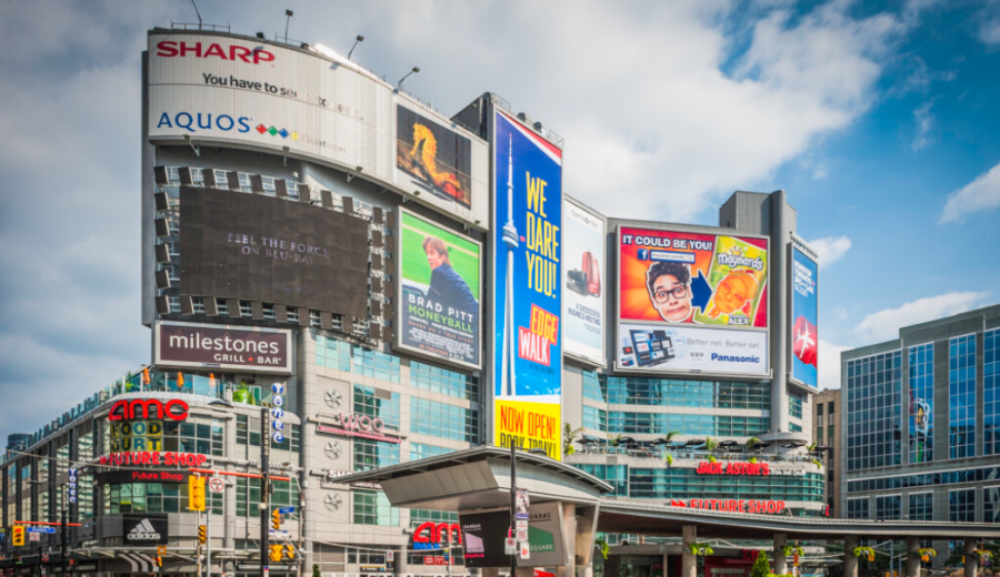 Busy downtown scene near Dundas Square in Toronto, where short-term rentals offer travelers a vibrant alternative to traditional hotel stays.