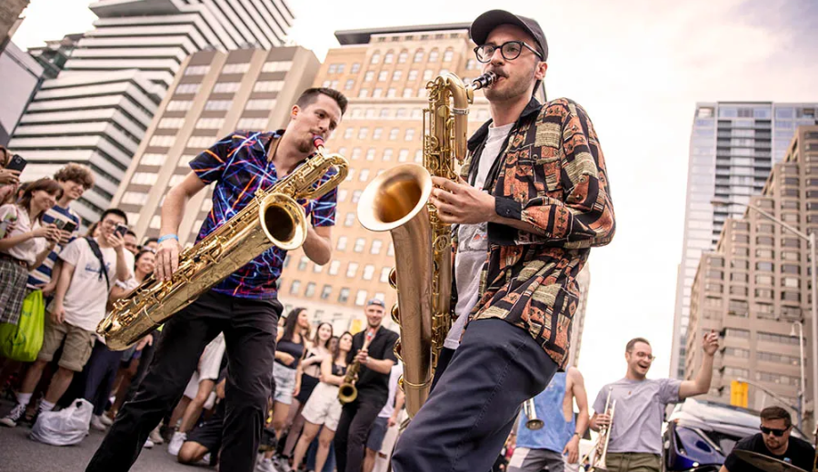 Saxophone duo ignites the streets with rhythm and flair at the 2025 Toronto Jazz Festival, drawing an enthusiastic crowd amid the city skyline.