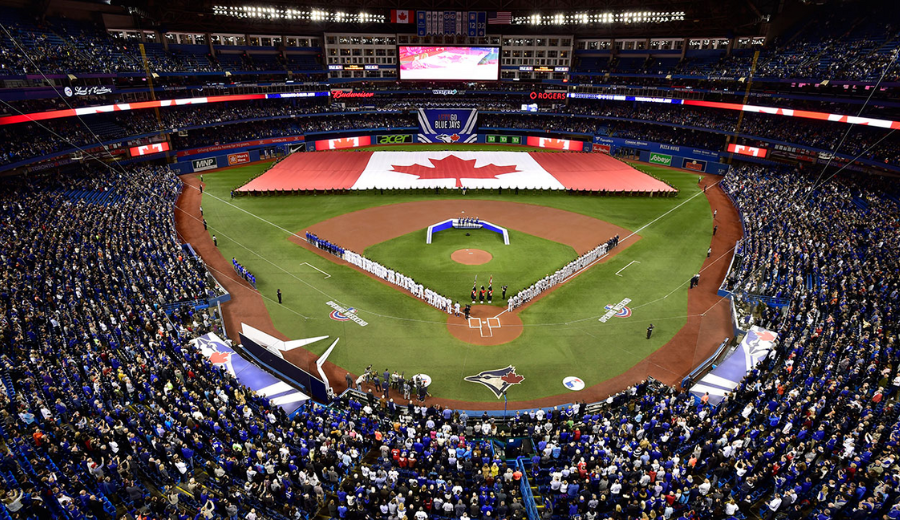 Panoramic view of Rogers Centre packed with fans as the Toronto Blue Jays prepare for a game under a giant Canadian flag display.