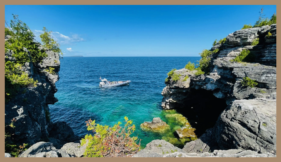 Toronto day trip destination Bruce Peninsula Grotto with turquoise water, cliffs, and a boat passing by