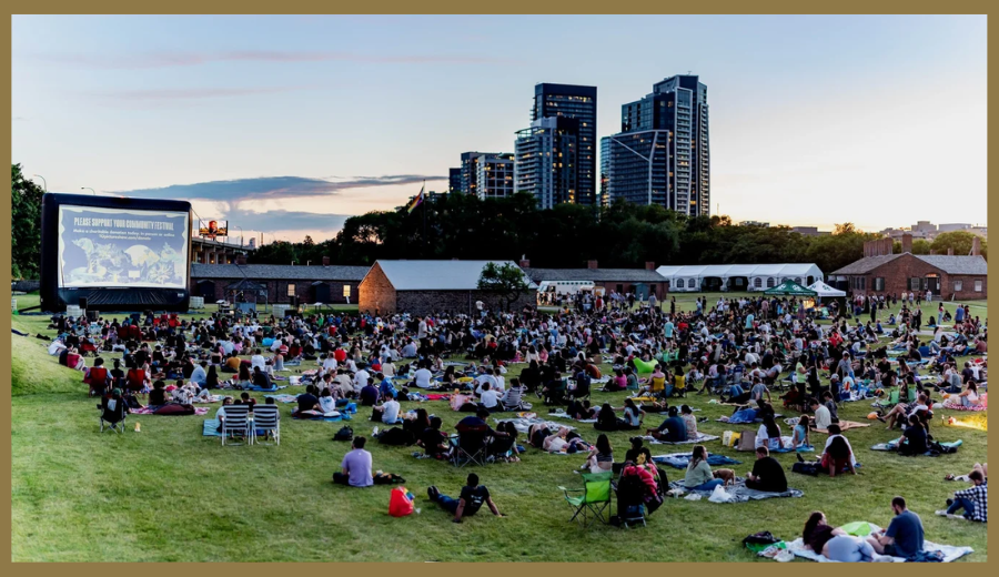 People gathered on blankets watching an outdoor movie at sunset