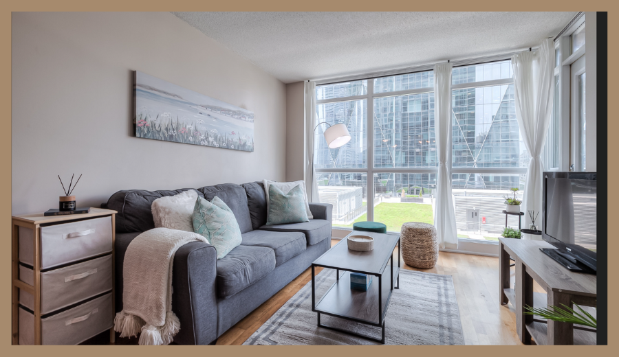 Stylish furnished apartment in downtown Toronto offered by RivetStays, featuring large windows and a cozy sofa.